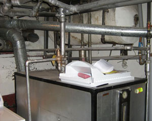 The original boiler - seen here - had to be removed and piping reconfigured.  The new arrangement tucks all of the heating equipment into a space under the stairs. Seattle garage plans builders