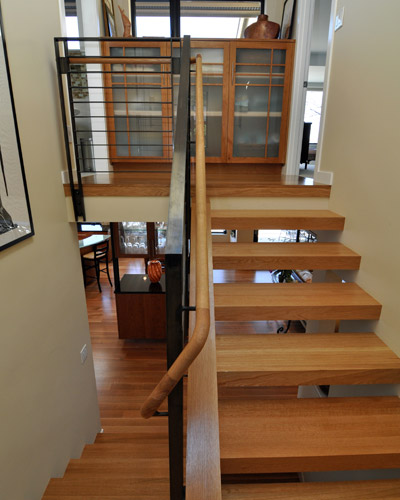 a contemporary open-tread system that lets light into the stairwell to the basement and has a peekaboo of the entry door