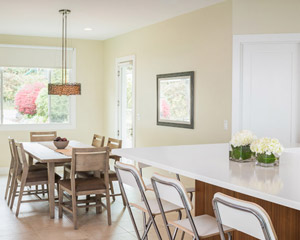 The dining room is just adjacent, and features a big window out into the front yard and access to the side yard.  The selection of a beachy light-colored wood table and chairs is just perfect