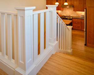Elegant white railings lead from the kitchen up half a floor to the master bedroom