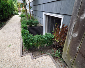 From the outside, new shrubbery delineates and will soon conceal the window wells.  Siding and window replacement at the main floor is the next planned project. Seattle basement design