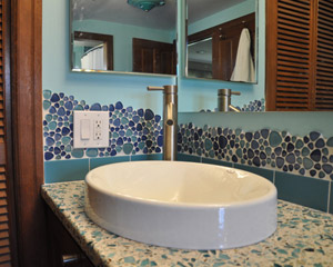 The new sink and faucet are contemporary, with clean lines.   The countertop is Vetrazzo, a terrazzo composite with aggregate in cool blue colors.  Bubble tile at the backplash bubbles up over the light switch