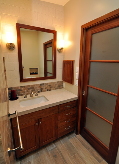 The vanity is also in mahogany, with the rich, red wood tones copied in the mirror frame and the custom medicine cabinet to the right.  The counter is Cambria Cardiff Cream.  Though the mirror you can see another nice carved out over the toilet, borrowing space from the adjacent attic