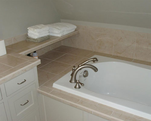 The master bath remodel features a soaking tub with a tiled shelf for towels