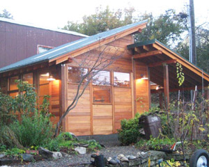 Careful placement of windows and doors, and an extra-tall entrance door brings lots of light into this cedar-clad shop and garage.  The framing elements were designed to be seen instead of hidden