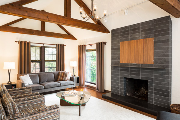 One element that required a complete overhaul was the living room fireplace.  The out-sized brick is now gone, replaced with black slate, and a raised, honed hearth in absolute black granite.  The same quartered walnut cabinets are used to cover a concealed television above the fireplace, with a rolled steel frame