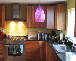The renovated kitchen is in the same location as the old one, but features cherry cabinets, granite counters and blown-glass pendant lights over the eating area
