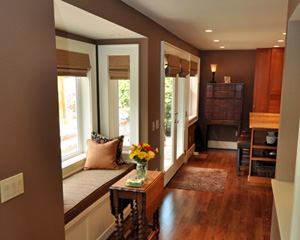 At the main level, a floor plan that formerly dead-ended at a stairwell to the basement is now a circular floor plan, with a space gallery.  The main floor bumpout allowed not only a hall connecting the kitchen and media room, but also a quaint and comfy bay, which doubles as an eating nook.  The built-in cabinetry has a lifting bench seat for storage, and looks out on the newly landscaped backyard