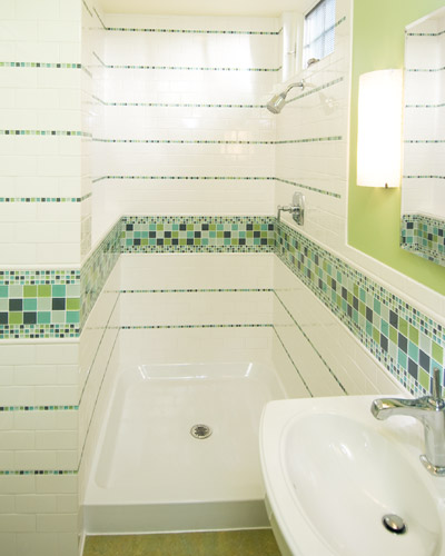 The tile and finishes in the guest bath are worthy of a master suite: Maniscolo Gosford glass tile runs throughout, with Marmoleum flooring as a color accent, a custome tile bathroom Seattle
