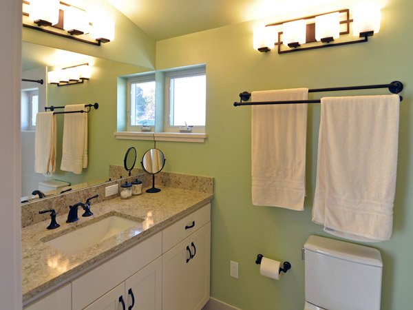 The bathroom is placed squarely in the corner of the new dormer, where it benefits from windows and bright interior colors. It includes a custom vanity and Pental cappuccino counters