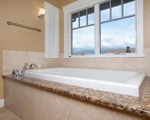 A splash of luxury: a drop-in tub set on an expansive granite deck.  A view of sky and water beyond makes this a private and relaxing oasis
