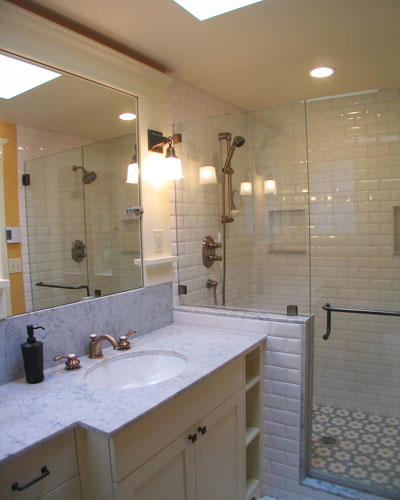 The small space in this Seattle bathroom remodel is maximized by using mirrors, windows and a frameless glass shower enclosure