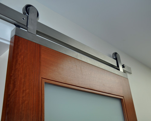 A custom built stainless piece at the top of the door connects the factory hardware to the door