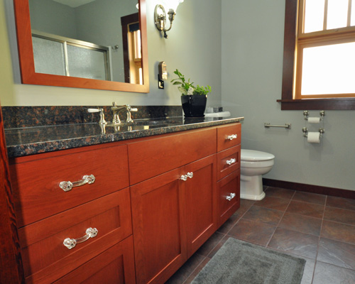 The master bathroom has the same custom cherry cabinets as the kitchen.  The cabinetmaker also fabricated the mirror frame, so all the wood and stain is consistent.  Warm colors continue with the floor tile