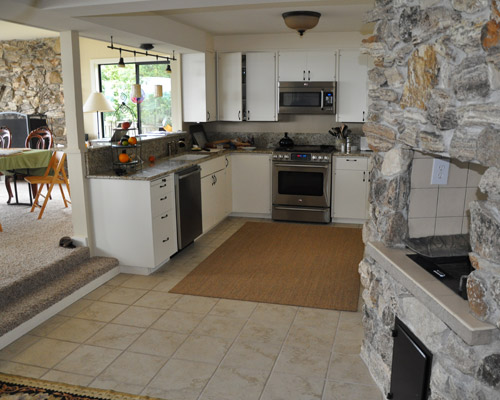 The kitchen had been outfitted with plain white cabinets and was dominated visually by a fireplace/cooking area that was going unused