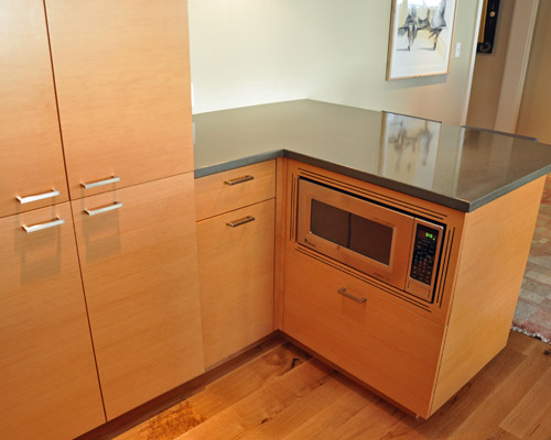 The refrigerator wall continues into a small peninsula and eating area with a microwave tucked into the corner