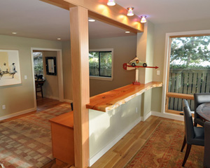 The wall divider here is topped with a live edge fir slab that doubles as seating on the dining room side