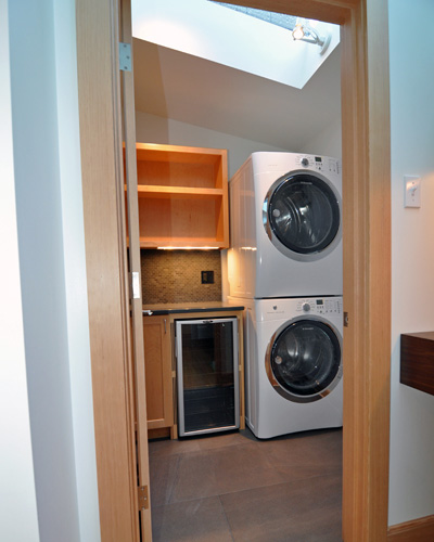 In the corner where the hot tub used to sit, there is now a beautifully appointed main floor laundry room, with stacking washer/dryer and a built-in wine cooler