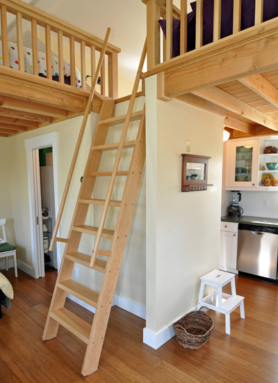 The ladder was designed and custom built to lift and pull out a few feet so that it's stable and easier to climb.  A matching wood railing keeps the edges of the loft safe