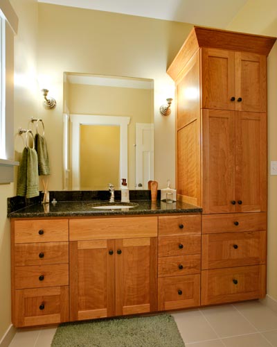 The shared kids bath benefits from a full-height linen cabinet in cherry, and Verde Butterfly granite counters