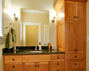 The shared kids bath benefits from a full-height linen cabinet in cherry, and Verde Butterfly granite counters