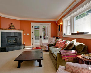 A comfortable, light and bright basement living room, with a salvaged wood mantle at the gas fireplace