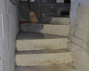 The original concrete stairs to the basement wound precipitously down from the garage. The concrete slab was uneven and ceilings low, with open cinderblock foundations walls visibly leaking moisture