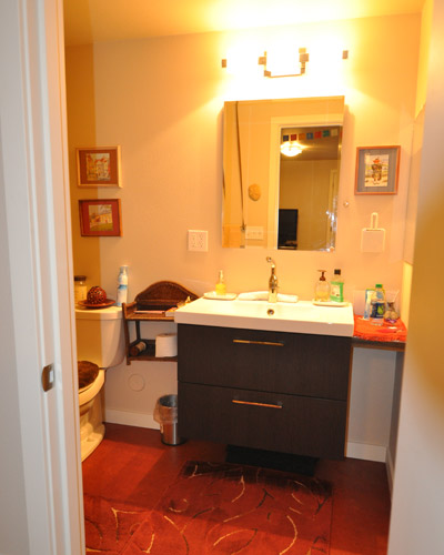 A bathroom off the main room includes an easy-to-clean acrylic tub and contemporary vanity, with bright Marmoleum flooring