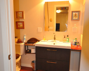A bathroom off the main room includes an easy-to-clean acrylic tub and contemporary vanity, with bright Marmoleum flooring