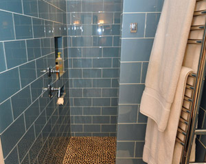 The shower is long enough that it allowed a design without a glass door.  The partition to the right helps contain spray, while the step-off area is an ideal location for the towel warmer and a robe hook