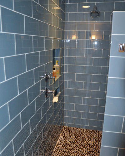 The large format glass tile provides some color and reflects light.  The effect is one of cool serenity.  The natural stone in the shower pan provides an organic element in the design