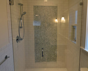 The shower features an acrylic pan with a covered grate, and a custom glass door