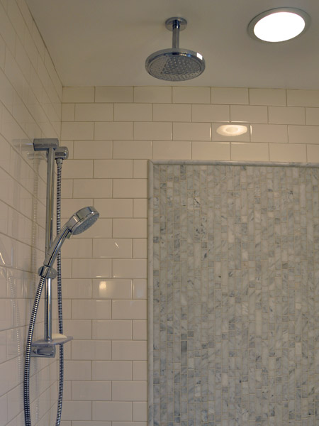 With a rain head and a hand-held shower head controlled by a diverter, it is possible to have a spa-like feel while showering and the convenience to easily clean the shower with the hand-held fixture.  The accent tile is marble installed vertically for a nice counterpoint to the horizontal lines of the subway tile