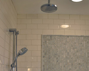 With a rain head and a hand-held shower head controlled by a diverter, it is possible to have a spa-like feel while showering and the convenience to easily clean the shower with the hand-held fixture.  The accent tile is marble installed vertically for a nice counterpoint to the horizontal lines of the subway tile