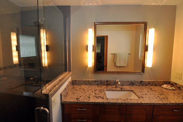 The cherry vanity by Kitchencraft is laid out with more functional drawers and doors, and the new electrical plan provides much better lighting for the room in this remodel Seattle rambler