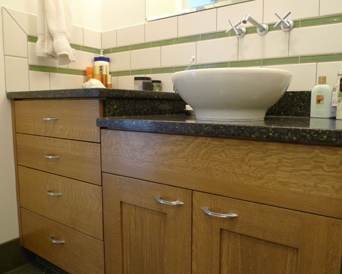 Granite counters split at each level, and a wall-mounted faucet provides interest at the vessel sink