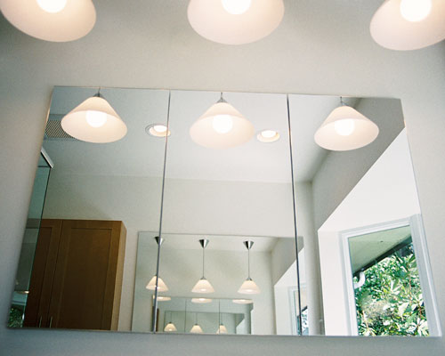 The final design element to improve the light and feeling of openness is mirrors.  A three-panel cabinet at the sink is reflected on the opposite wall with a single large mirror.  It's amazing how all of these design elements work together to make this very small space feel spacious.