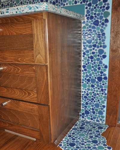 At the end of the countertop, the tile 'flows' down the wall and into a pool on the floor, a unique and colorful installation