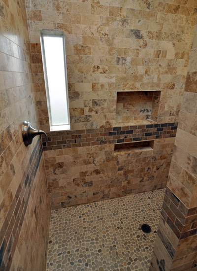 Inside the shower, a generously sized niche provides lots of space for shampoo and soaps.  The controls for the shower are at the left, which allows a warmup of the water without getting wet first.  The shower floor is pebbles with natural stone on all walls