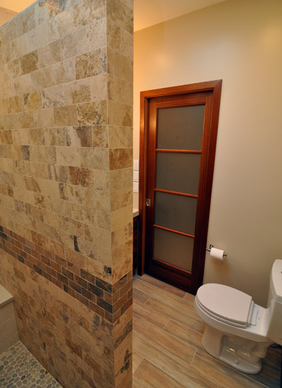 Exiting the shower, you can see the new mahogany pocket door, also with obscured glass.   The slat floor tiles pick up the colors in the wood with hints of wood grain