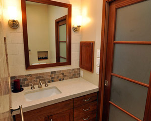 The vanity is also in mahogany, with the rich, red wood tones copied in the mirror frame and the custom medicine cabinet to the right.  The counter is Cambria Cardiff Cream.  Though the mirror you can see another nice carved out over the toilet, borrowing space from the adjacent attic