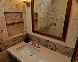 There is also a small niche to the left of the sink, with a mahogany sill in the middle.  The tile from the shower wraps all the way around and then makes a change to a lighter tile at the vanity