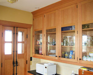 On the opposite side of the kitchen is a wall of built-in custom cabinetry, complete with old-fashioned bubbly glass.  The new door to the deck is a custom French door, complete with a Cremone bolt.   All of the switches are traditional push-button, with a dark finish, a perfect Seattle custom kitchen cabinet