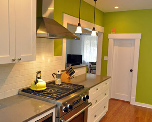 The new range and exhaust hood provide modern convenience, set off by subtle quartz counters by Pental. The range is also a huge improvement over the previous range, which sat by itself on an adjacent wall, blocking the flow of traffic. Brightly painted walls bring a pop of color to this otherwise neutral space
