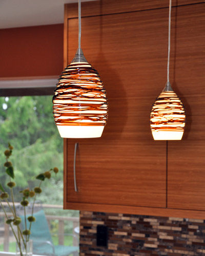 Unique pendants over the seating bar draw from the same color palette as the stone backsplash and countertop