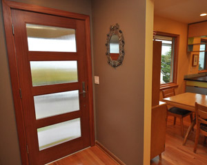The new mahogany door has reed glass and clean lines, providing privacy while bringing in light to another otherwise dark entry on this home entry remodel Seattle