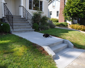 Wrought iron railings finish out the look, and a newly poured walk and short stair by the sidewalk make the entry inviting